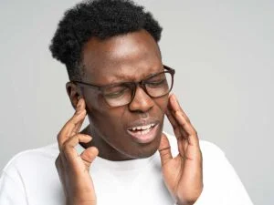 African American man holding his ears in pain