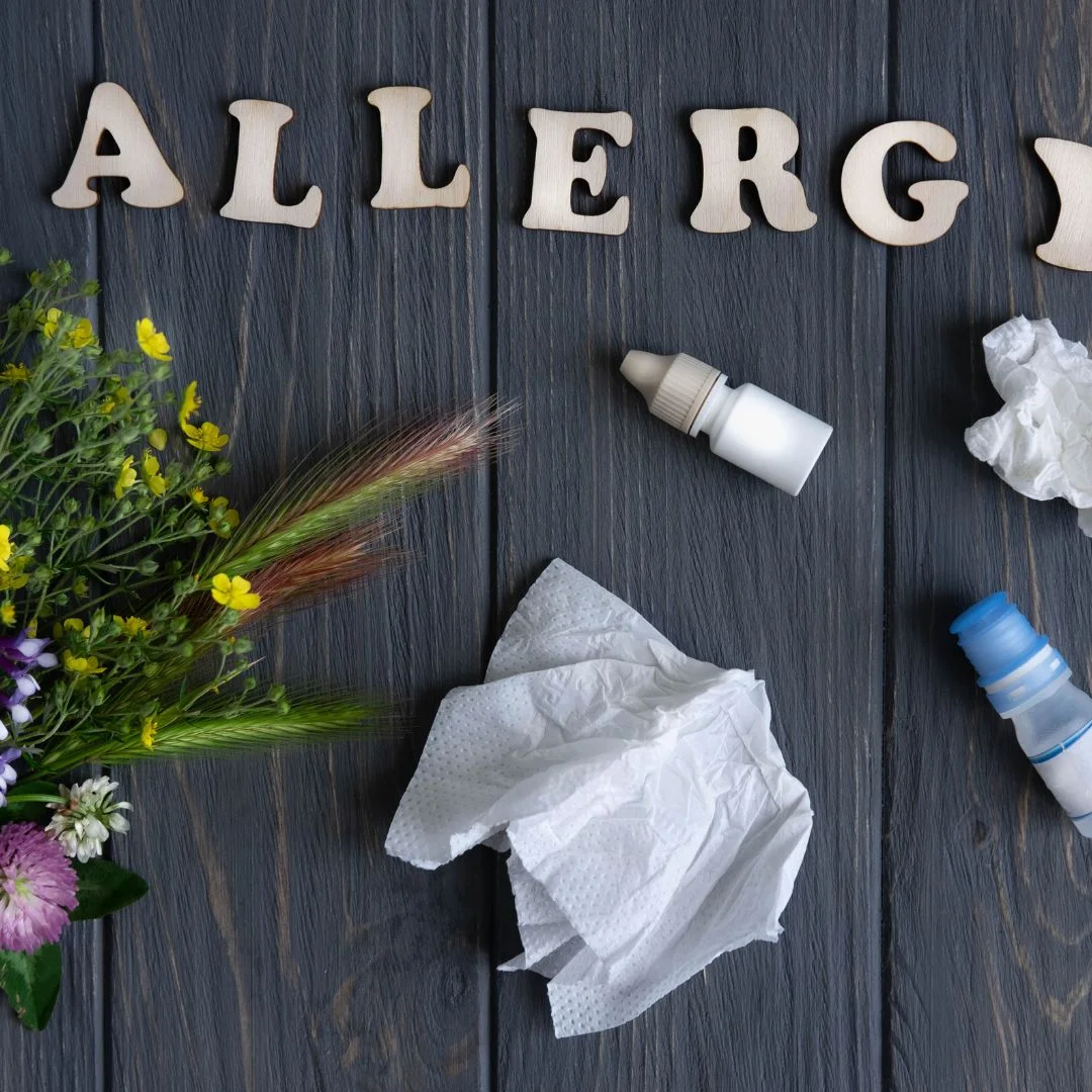 tissues, bottles, flowers and the word allergy spelled out