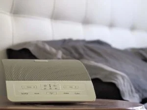 A white noise machine next to a person's bed