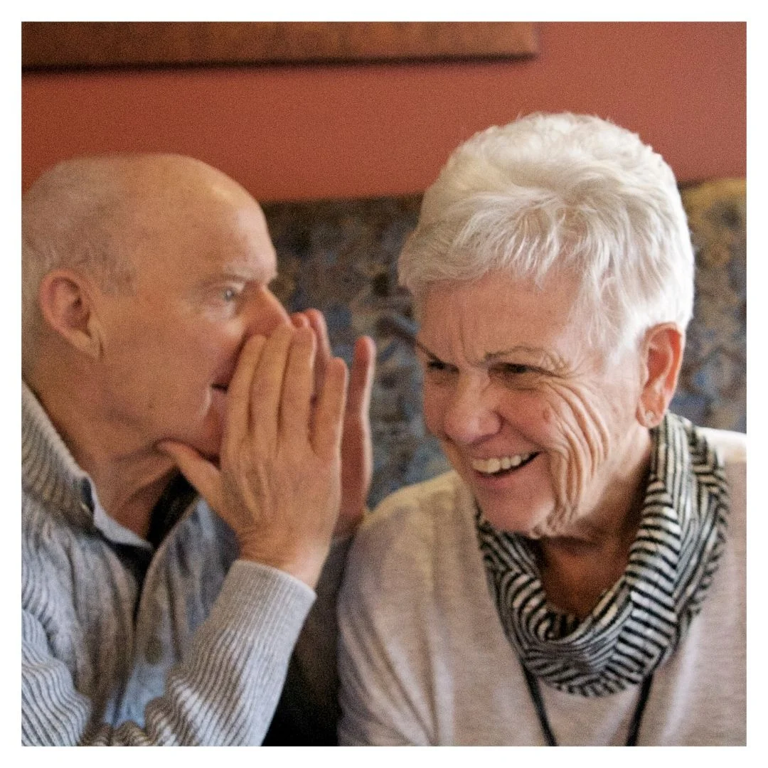 man talking into woman's ear